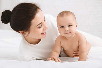 Adorable baby trying to crawl along white bed