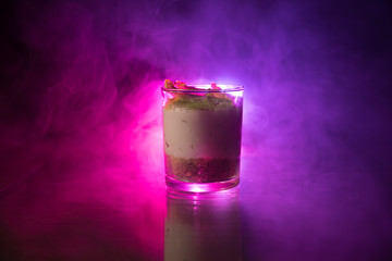 Sweet cheesecake in glass on a table with toned foggy backglight.