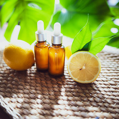 Bottles with lemon oil, fresh  fruit whole and half on a natural tropical background.