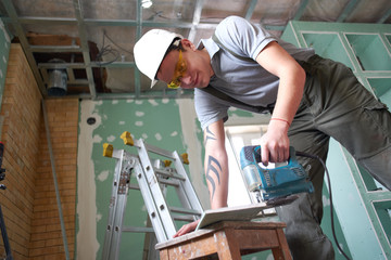 Room repair. Building. Worker cuts profile for drywall on the background of the construction site