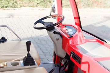 Empty cab and old model steering wheel of red colored open touristic minibus in Byala, Bulgaria.