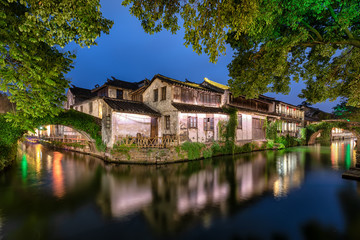 Fototapeta na wymiar Die Kanäle, Brücken und alte Gebäude der antiken Wasserstadt Zhouzhuang bei Shanghai in China am Abend