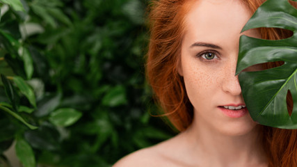 Fototapeta premium Portrait of young and beautiful woman in tropical leaves