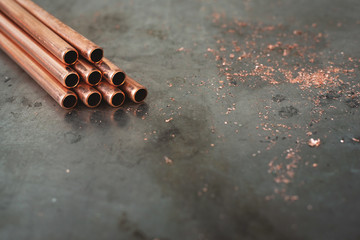 Stack of brass pipes on a fitter workbench background with copy space.