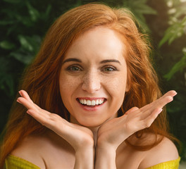 Cheerful redhaired girl smiling at camera on green