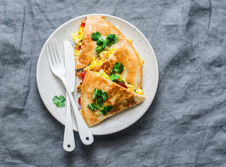 Scramble eggs vegetables ham quesadilla on a grey background, top view. Delicious appetizers, tapas, breakfast