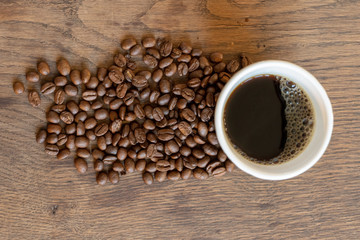 coffee cup with coffee in surrounded by coffee beans