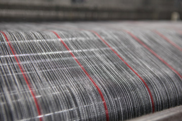 Yarn thread lines on the weaving loom machine. A loom machine for clothing or woven label. Weaving machine for garment industry. Weaving loom in textile factory.