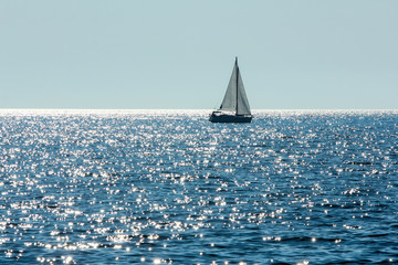 A picture single boat floating on the blue ocean during the hot summer day. Relaxing vacation activity for the people. 