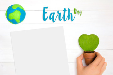 Hand holding heart shape green plants and global planet over white wooden background with copy space. Happy mother earth day. Top view. Flat lay.