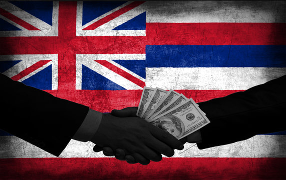 Two men/politicians in suits holding money/US Dollars and shaking hands with the national flag on the background - Hawaii - United States