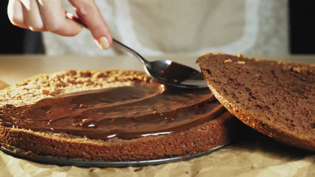 Woman spreading a cream on the baked dough.