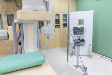 Vital signs monitor and large C-arm angiograph, operating room with X-ray medical scan in hospital.