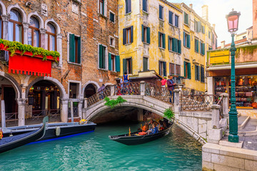 Narrow canal with gondola and bridge in Venice, Italy. Architecture and landmark of Venice. Cozy cityscape of Venice. - obrazy, fototapety, plakaty