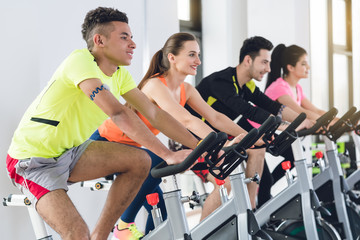 Group of young friends cycling in row at gym