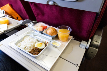 Basic inflight meal consisting rice, egg, beef curry, bread, juice.