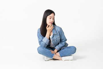 Thinking asian woman sitting on floor isolated on white background.Asian female model smiling looking up.woman pointing fingers away while sitting on a floor with legs crossed isolated