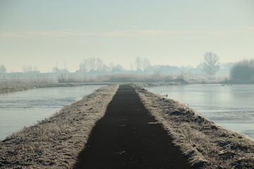 Frozen meadows and water with fog during colorful sunrise in Park Hitland at Nieuwerkerk aan den IJssel in the Netherlands