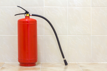 Fire extinguisher bright red isolated on white light tiles walls and floor copy space background....