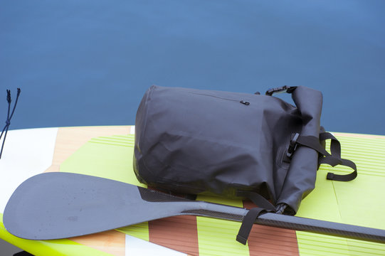 black backpack placed on surf board on water