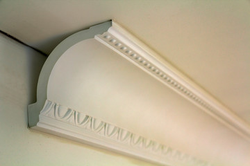 Close-up detail of decoration white molding connected with glue adhesive to wall and ceiling in interior room renovation and reconstruction. © bilanol