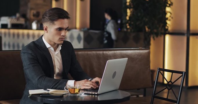 Young businessman using laptop computer sitting at the cafe table