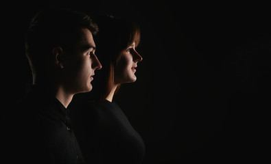 Portrait of a man and a woman in a low key. Closeup of young couple side view. Dramatic portrait