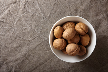 Bowl of walnuts on linen cloth. Background with copy space.