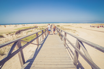 Fototapeta na wymiar Couple walking on white bright walking path from the ocean land on the white beach