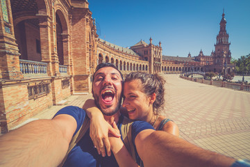 Naklejka premium szczęśliwa uśmiechnięta para robi selfie na placu Hiszpanii (Plaza de Espana) w Sewilli w Hiszpanii