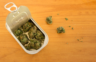 Tin can with high quality marijuana buds on wooden background with copy space right. Hidden drug. Packaged marketed marijuana with a secure method.