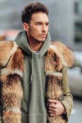 Fashionable man walk outdoors wear  fur jacket with street background - Image