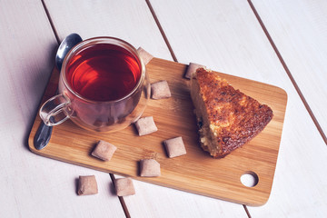  Tasty breakfast. A cup of tea, baked pie and sweets on a wooden table.