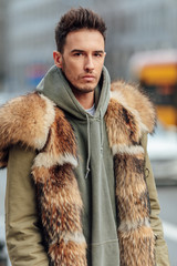 Fashionable man walk outdoors wear  fur jacket with street background - Image
