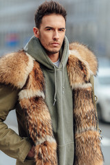 Fashionable man walk outdoors wear  fur jacket with street background - Image