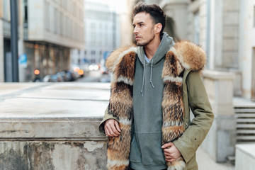 Fashionable man walk outdoors wear  fur jacket with street background - Image