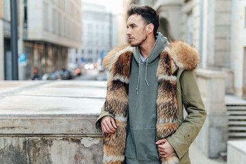 Fashionable man walk outdoors wear  fur jacket with street background - Image
