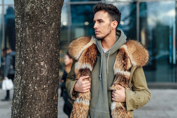 Fashionable man walk outdoors wear  fur jacket with street background - Image
