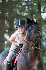 Obraz premium Portrait of black horse with cheerful teenage girl equestrian