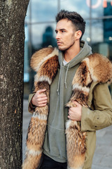 Fashionable man walk outdoors wear  fur jacket with street background - Image