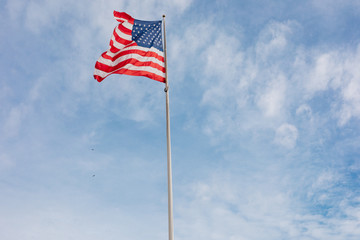 American flag on the blue sky with clouds