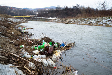 polluted river in winter, plastic pvc bottles floating on the water