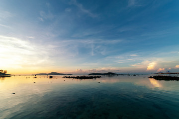 Obraz premium Dramatic sky seascape with rock in sunrise scenery and beautiful reflection in the sea