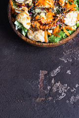 Healthy balanced dinner. Buddha bowl lunch with couscous, turkey, carrot, salad mix and sesame. Dark brown concrete background. Copy space. 
