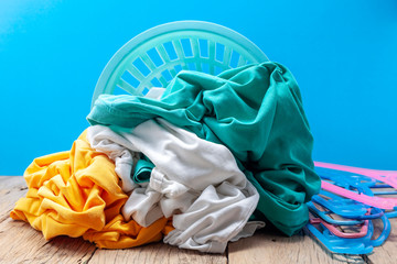 Pile of dirty laundry in washing basket on wooden,blue background