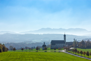 Herbstlicher Blick vom Irschenberg in Bayern auf die Wallfahrtskirche St. Marinus und die Alpen