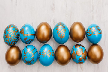 Fototapeta na wymiar golden decorated easter eggs on white wooden background