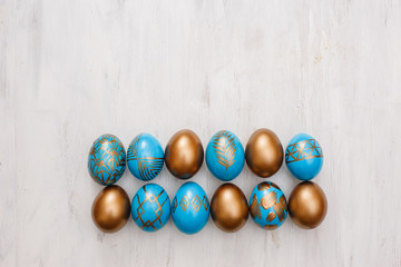 Obraz na płótnie Canvas golden decorated easter eggs on white wooden background