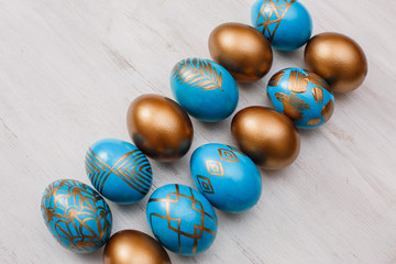 golden decorated easter eggs on white wooden background