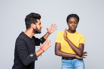 Portrait of mixed race couple african woman and indian man sort out relationships, look in displeasure at each other, have quarrel stand against white background. Interracial family face some problems